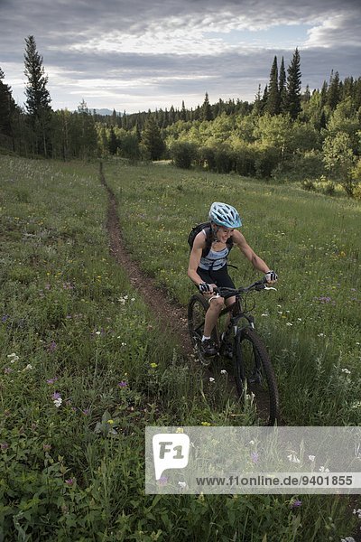 A mountain biker happily rides a single track.