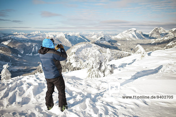 Skier photographing winter landscape.