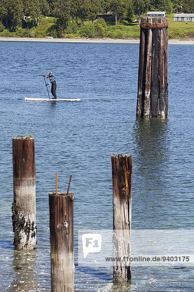A man paddling a stand up paddle board in Port Gamble  Washington.
