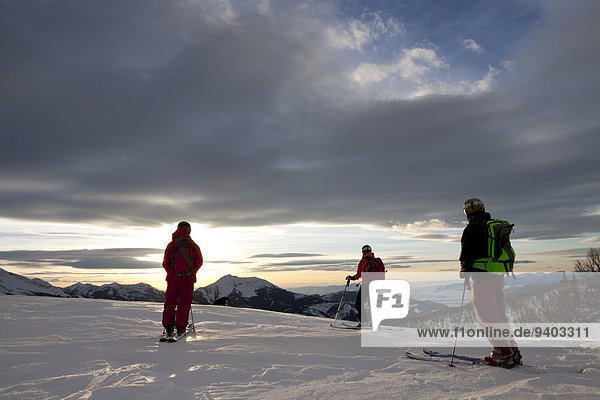 Three backcountry skiers and their dog at sunset in the Beehive Basin near Big Sky  Montana.