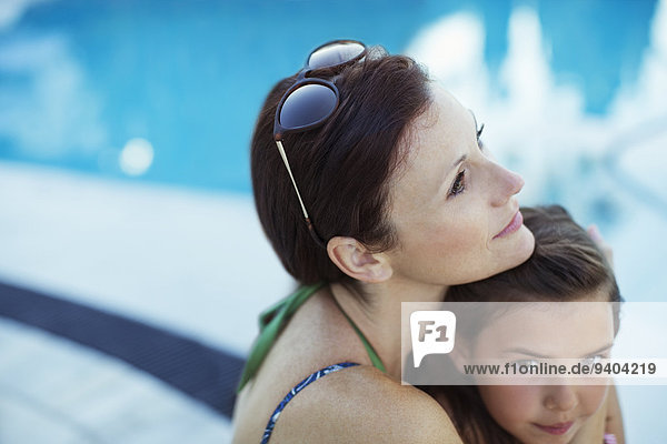 Nachdenkliche Frau sitzend am Pool mit Tochter