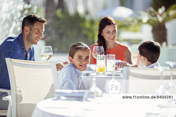 Familie mit zwei Kindern beim Abendessen im Resort im Freien