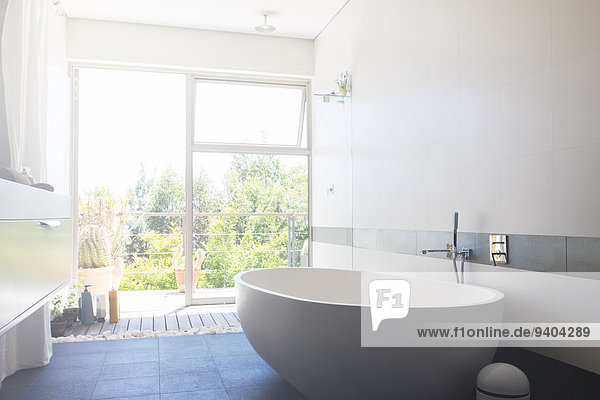 Modernes Badezimmer mit großer weißer Badewanne und Terrassentür