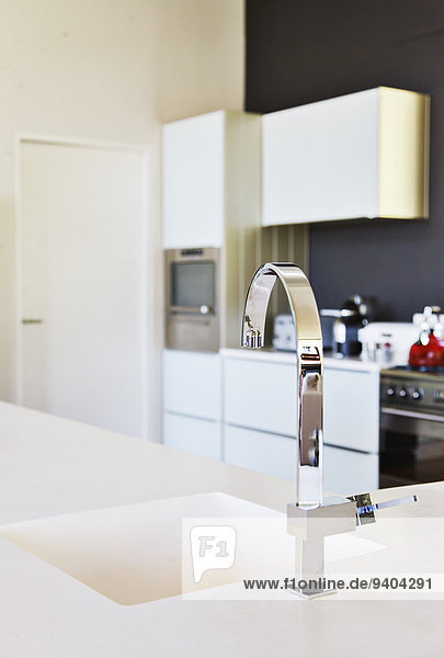 Moderne Edelstahlarmatur und weiße Spüle in sauberer Küche