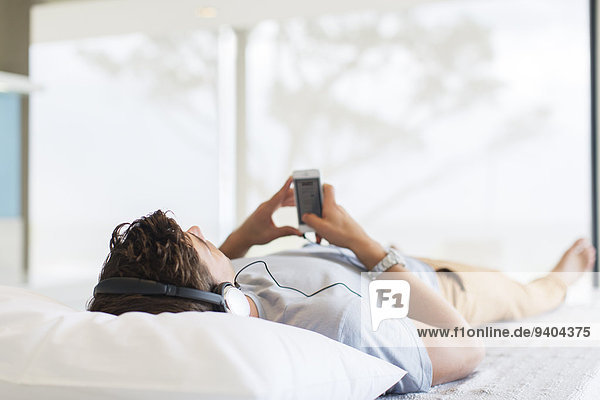 Man listening to music while lying on bed