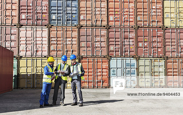 Arbeiter und Geschäftsleute im Gespräch in der Nähe von Frachtcontainern