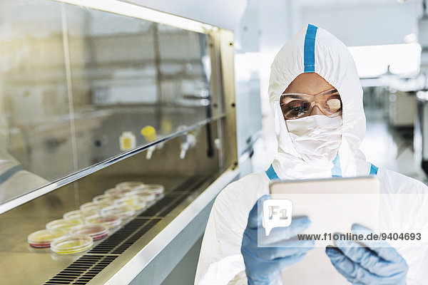 Scientist in clean suit using digital tablet in laboratory