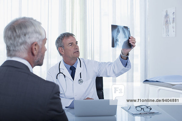 Doctor sitting at desk in office examining patient's x-ray