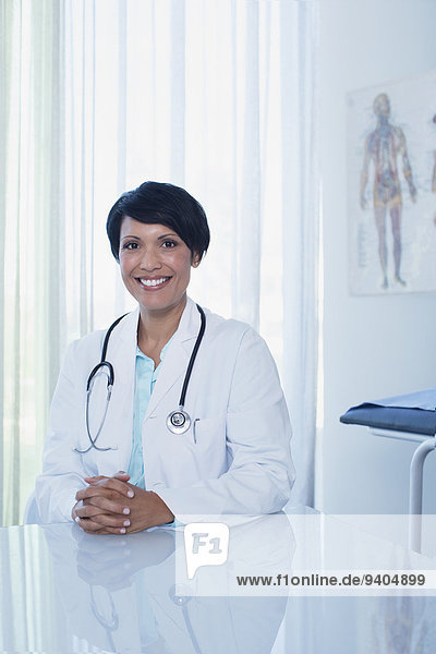 Portrait of smiling female doctor sitting at desk in office