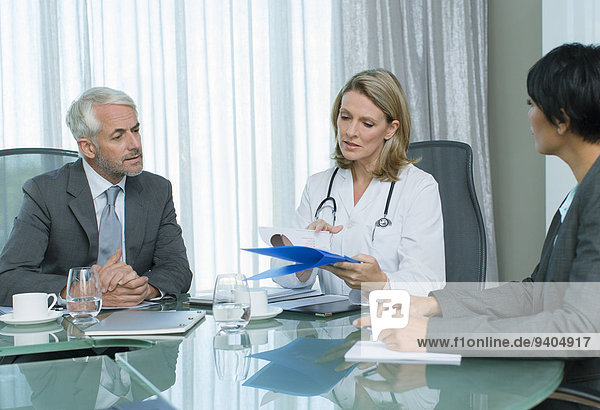 Ärztin  Mann und Frau beim Gespräch am Tisch im Konferenzraum