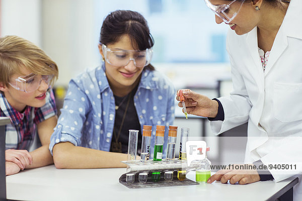 Lehrer und Schüler im Chemieunterricht  mit Schutzbrille und Blick auf Reagenzgläser