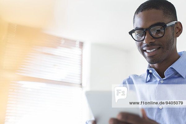 Porträt eines jungen Geschäftsmannes mit Brille und digitalem Tablett im Büro