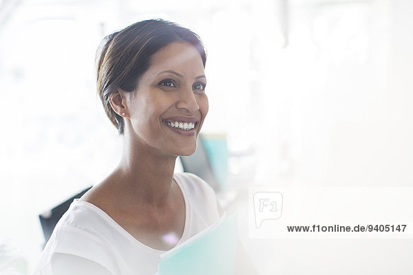 Portrait of smiling woman holding documents in office