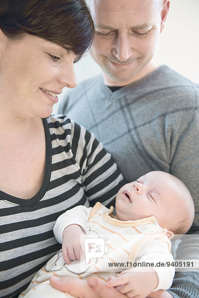 Parents holding their baby boy in arms  smiling