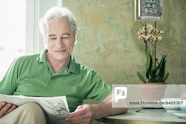 Mature man reading newspaper  smiling
