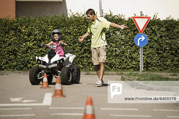 Tutor and girl with quadbike on driver training area