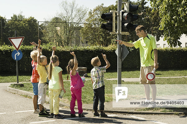 Tutor and children at traffic light on driver training area