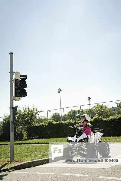 Girl with quadbike waiting at traffic light on driver training area