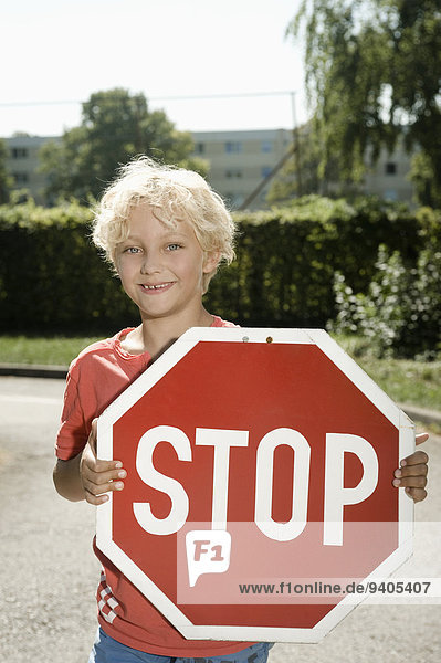 Boy on driver training area holding stop sign