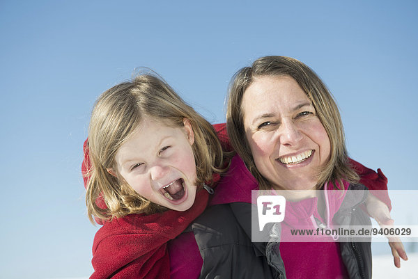 Mother giving piggyback ride to daughter  smiling