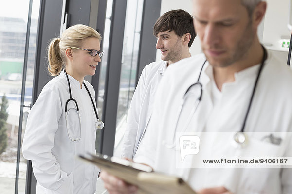 Doctor reading file while colleagues in background