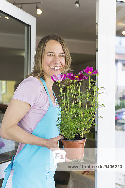 Portrait Frau Blume lächeln halten Pflanze Mittelpunkt Topfpflanze Erwachsener