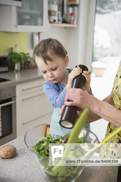 Boy helping his mother to pepper salad