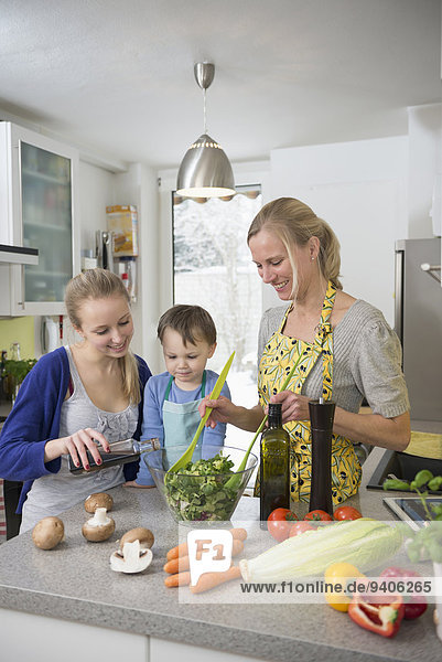 Mother and children preparing salad in kitchen  smiling