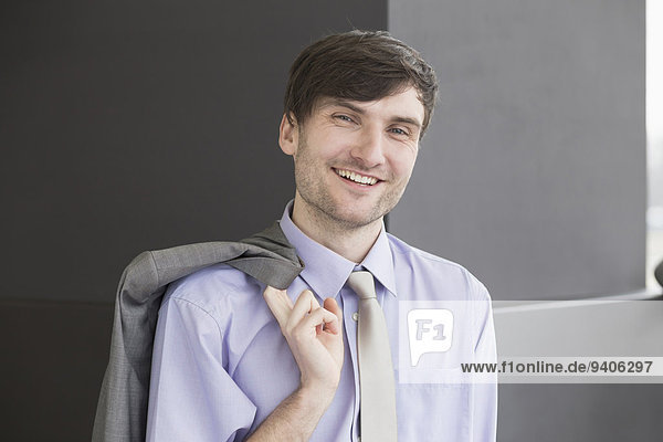 Portrait of businessman holding suit  smiling