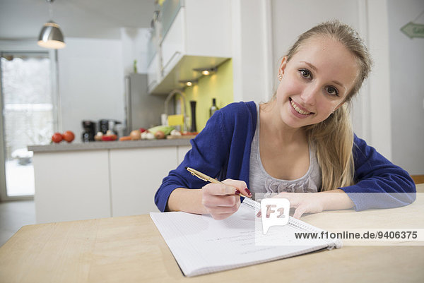 Portrait of teenage girl writing notes  smiling