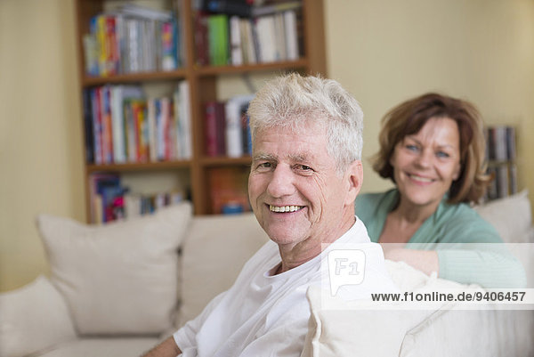 Portrait of senior couple sitting on couch in living room  smiling