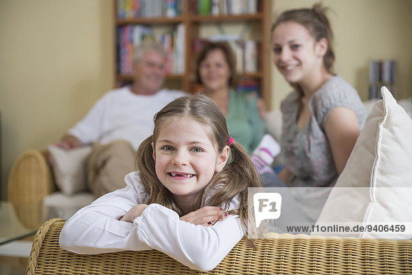 Portrait of grandparents and granddaughters sitting on couch  smiling