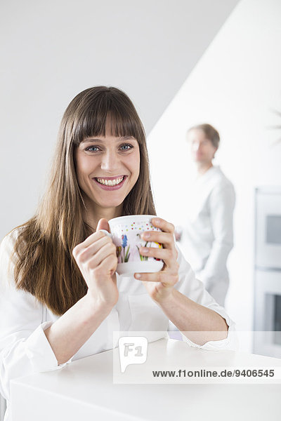 Portrait of woman with cup of coffee while man in background