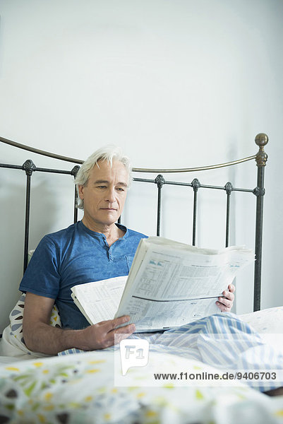 sitzend Mann Bett reifer Erwachsene reife Erwachsene Zeitung vorlesen