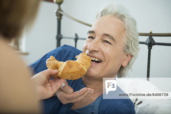 Frau Mann lächeln Croissant füttern
