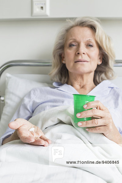 Patient in hospital holding cup and pills