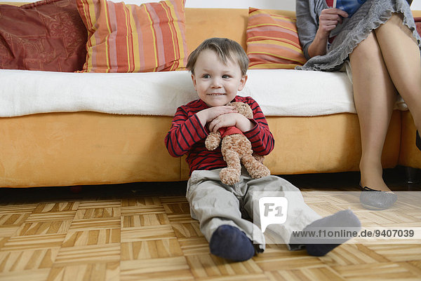 sitzend Boden Fußboden Fußböden lächeln Junge - Person Teddy Teddybär