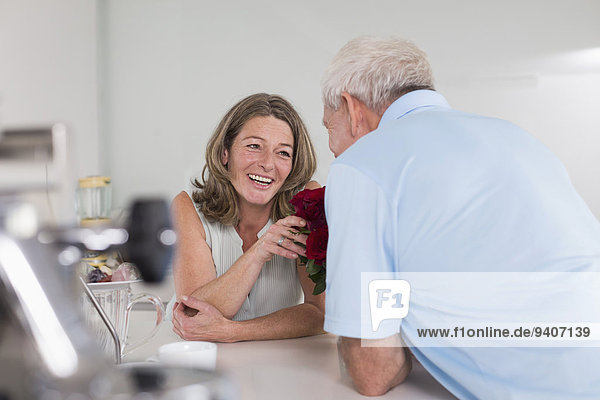 Senior man giving red roses to woman