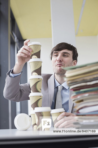 Businessman building tower with coffee cups  smiling