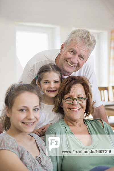 Portrait of grandparents and granddaughters in living room  smiling