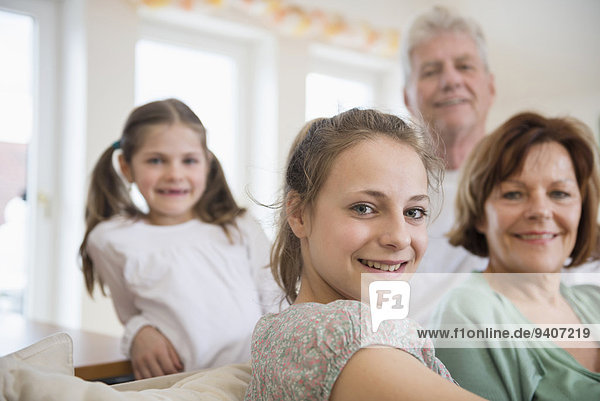 Portrait of grandparents and granddaughters in living room  smiling