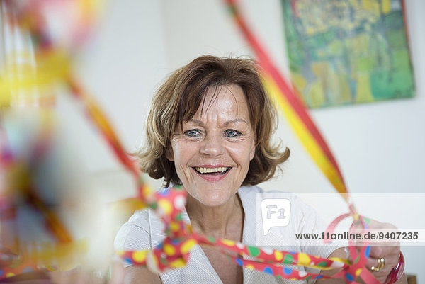 Portrait of senior woman with blowout paper streamer  smiling