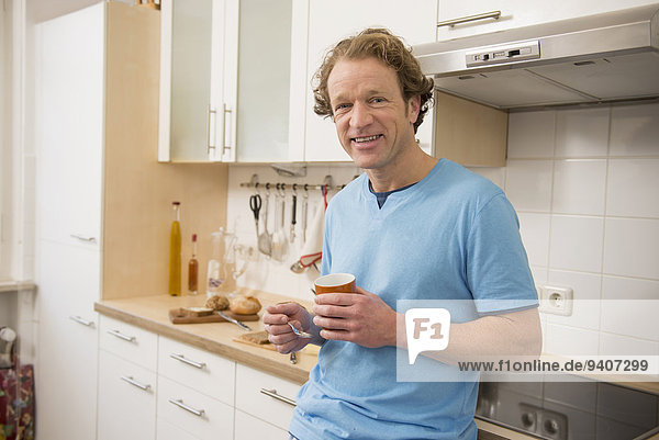 Smiling man with cup of coffee in kitchen