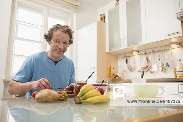 Smiling man sitting at breakfast table in kitchen