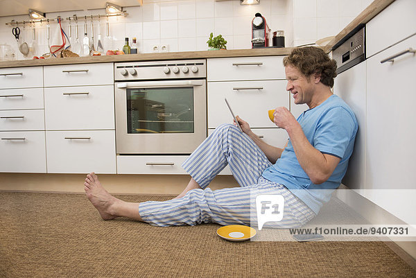 Man in pajama using digital tablet in kitchen