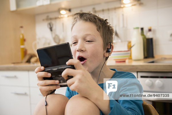Boy playing video game in kitchen