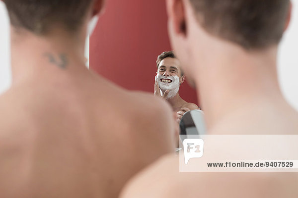 Homosexual couple having fun while shaving  smiling