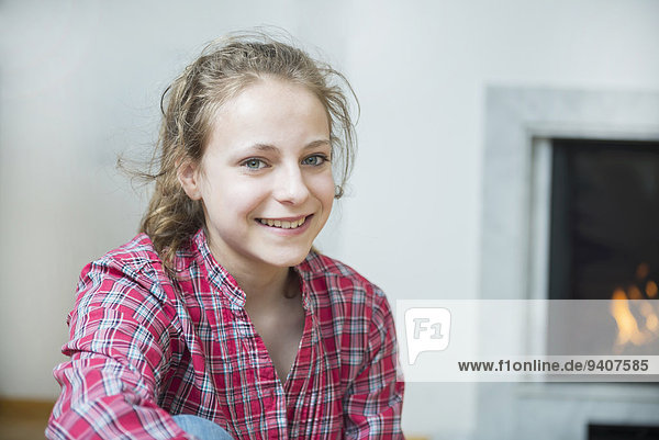 Portrait of girl sitting in front of fireplace  smiling