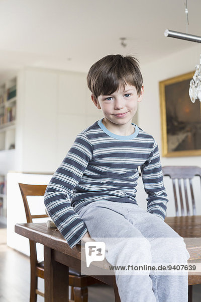 Portrait of boy sitting on table  smiling
