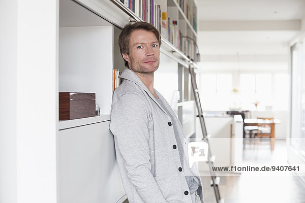 Portrait of mature man standing infront of bookshelf